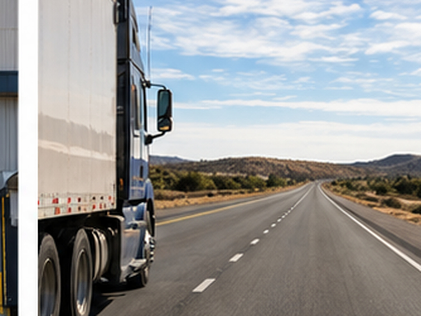 Empty tractor-trailer traveling on an open interstate with no freight activity visible around it.